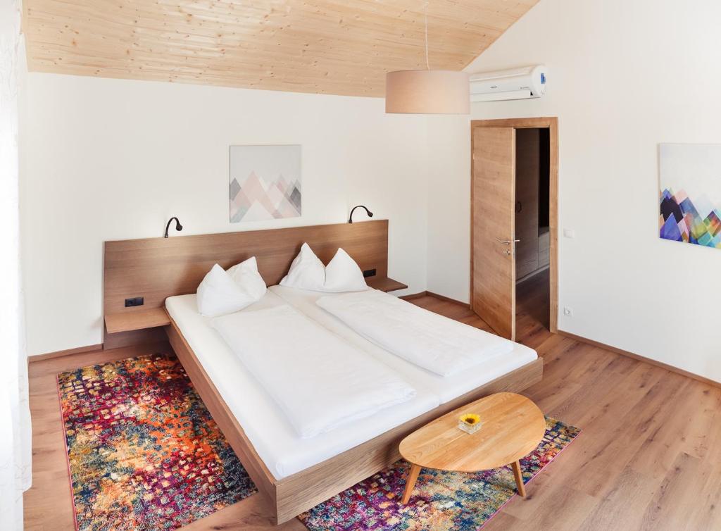a bedroom with a large white bed with a wooden headboard at ad vineas Gästehaus Nikolaihof-Hotel Garni in Mautern