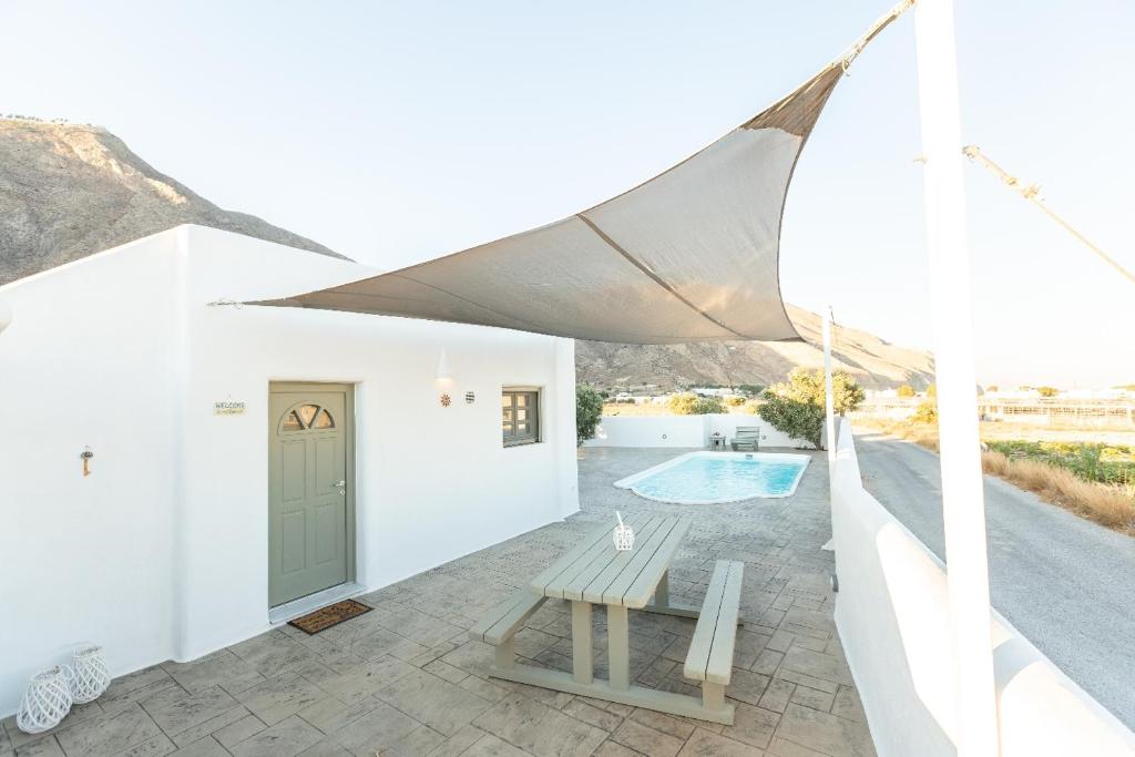 une maison blanche avec une piscine et un parasol dans l'établissement Elixirium villa, à Perissa