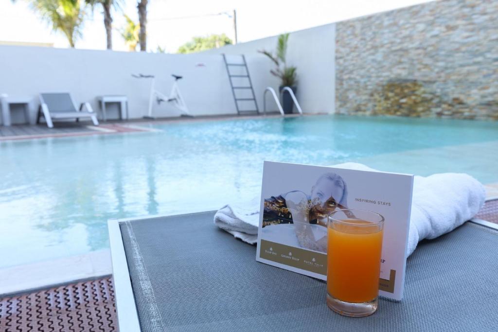 a glass of orange juice sitting on a table next to a pool at Tulip inn Sainte Clotilde in Saint-Denis