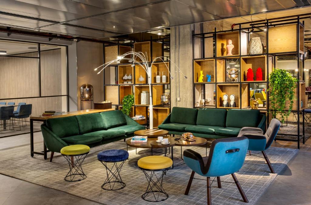 - un salon avec des canapés verts, des tables et des chaises dans l'établissement Link Hotel & Hub By Dan Hotels, à Tel Aviv