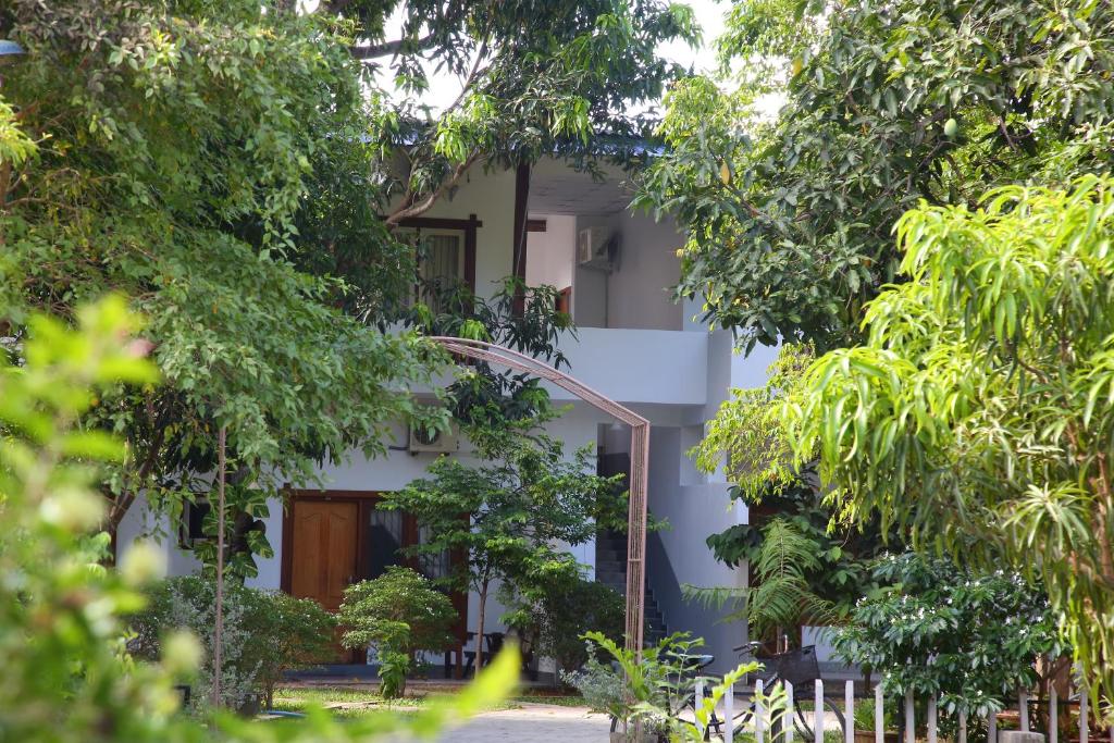 un edificio blanco con árboles delante de él en The Yala City Guest House, en Tissamaharama