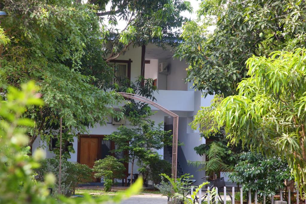 a white building with trees in front of it at The Yala City Guest House in Tissamaharama