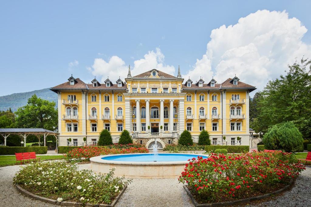 a large yellow building with a fountain in front of it at Grand Hotel Imperial in Levico Terme