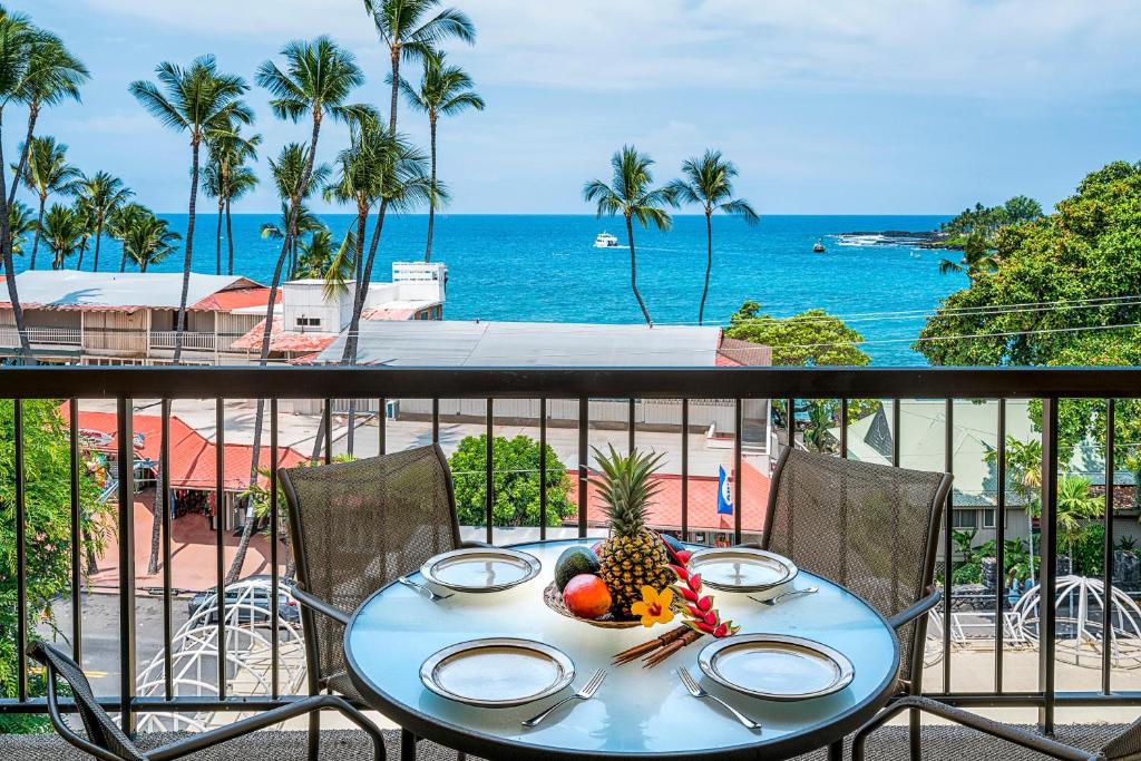 una mesa con piña en un balcón con vistas al océano en Kona Plaza#402, en Kailua-Kona