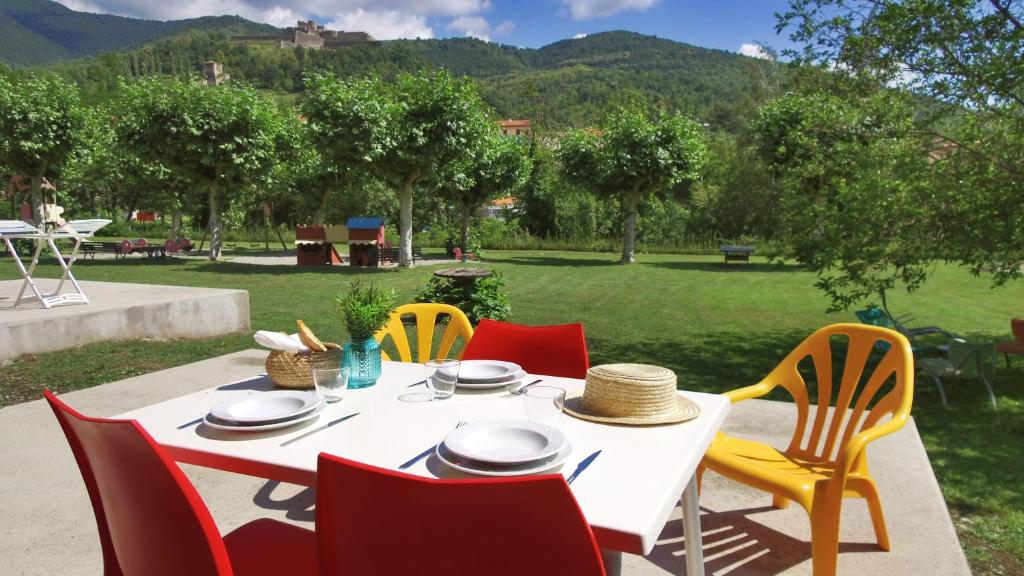 uma mesa branca com cadeiras vermelhas e amarelas num quintal em VVF Pyrénées Canigou em Prats-de-Mollo-la-Preste