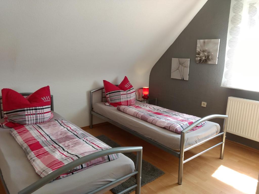 2 camas en una habitación con almohadas rojas en Ferienwohnung Dernbecher, en Saarbrücken