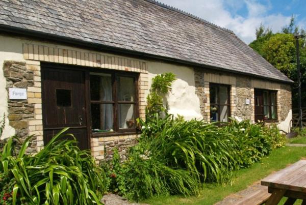 a small stone house with a bench in front of it at Forge Cottage in Merton