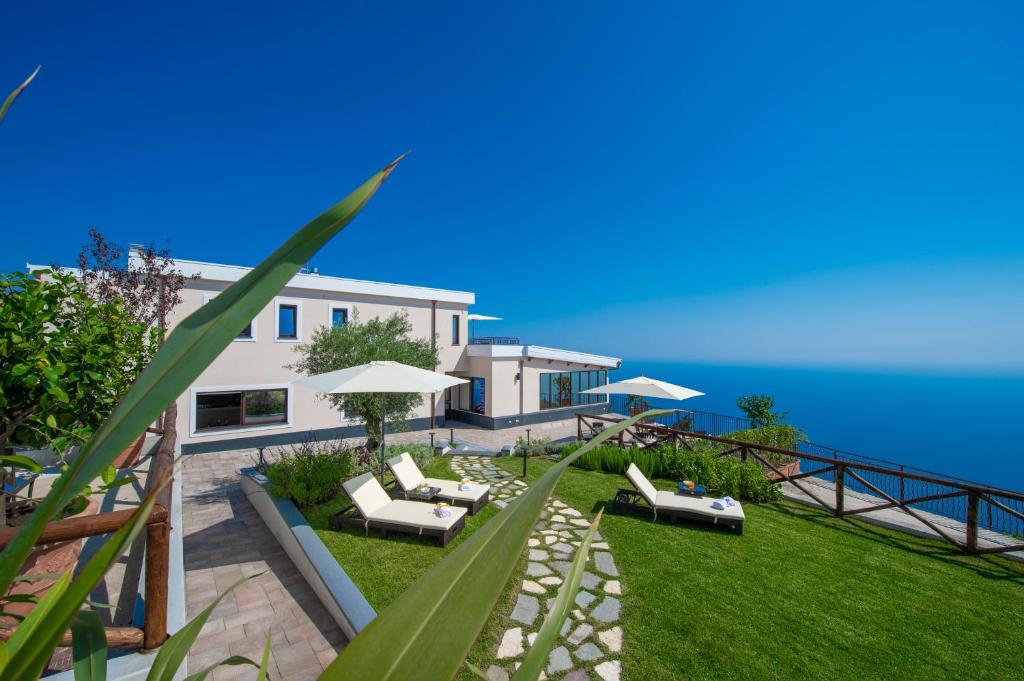 een huis met een gazon met stoelen en parasols bij Villa Paradise Resort in Agerola