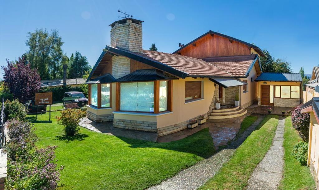 una casa con un césped verde delante de ella en Casa Labian Cabañas en San Carlos de Bariloche