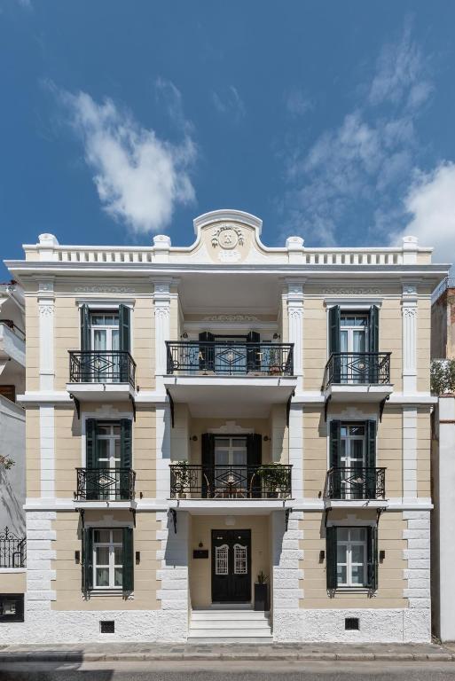 a white building with balconies and a clock on it at The Anthemion House in Kavala