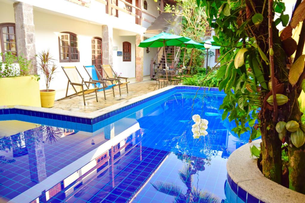 uma piscina com piso de azulejo azul e um guarda-sol em Magnu´s Pousada em Paraty