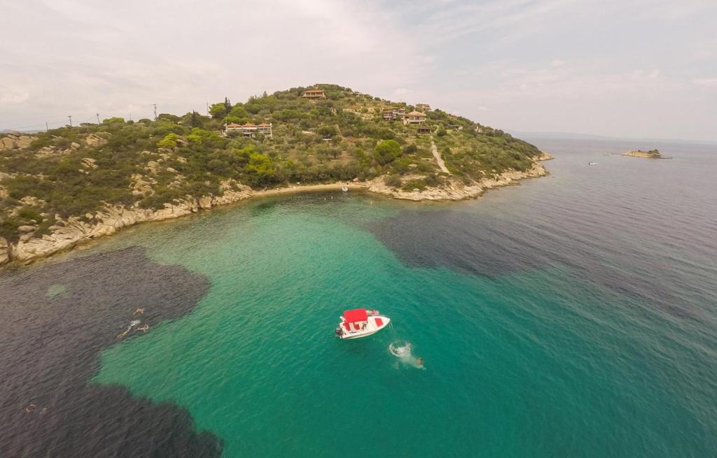 an island with a red boat in the water at Thalassokipos in Vourvourou
