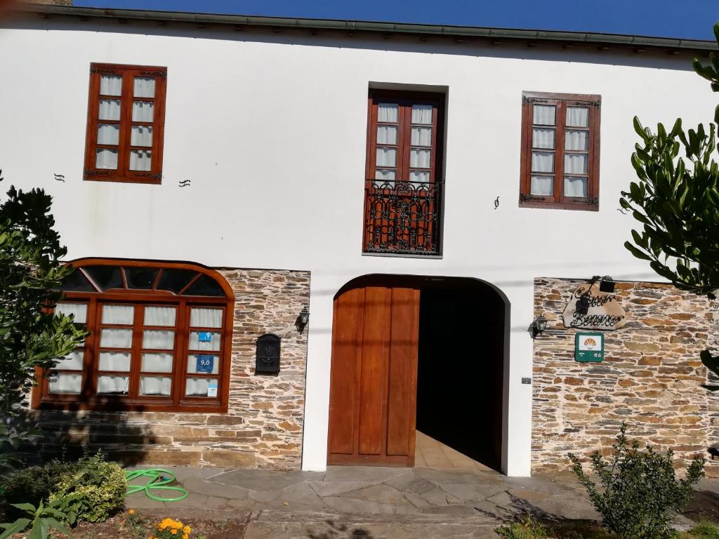 een wit huis met een houten deur en ramen bij Casa Benaxo in Currelos