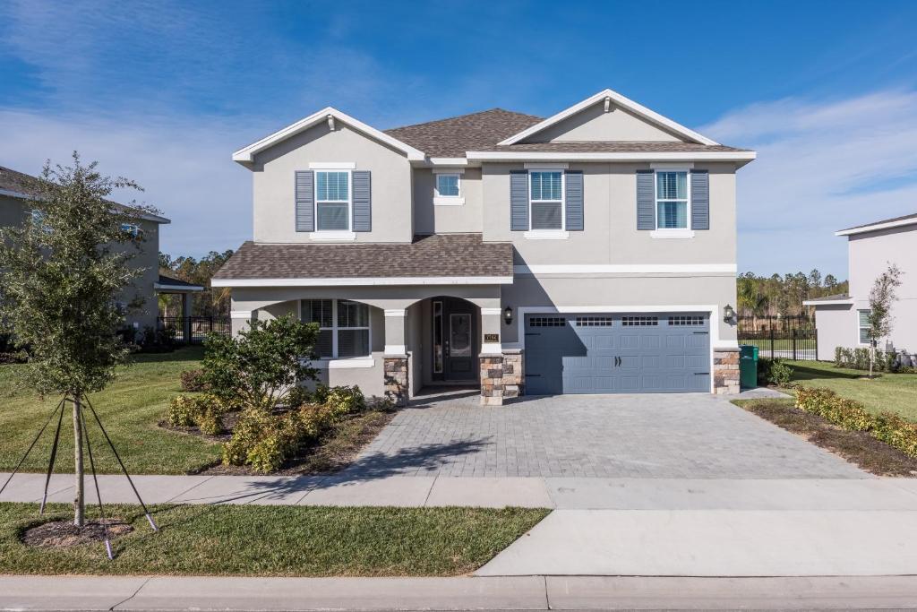 a white house with a driveway at Striking Home with Games & Outdoor Kitchen near Disney by Rentyl - 7742F in Orlando
