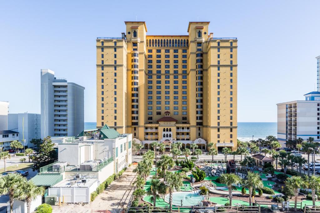 a large yellow building with a pool in front of the ocean at Anderson Ocean Club and Spa by Oceana Resorts in Myrtle Beach