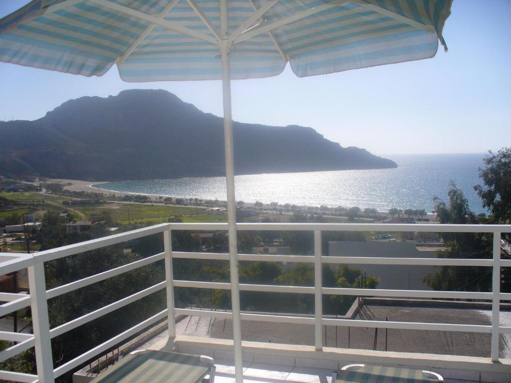 balcón con sombrilla y vistas al océano en Camelia, en Plakias