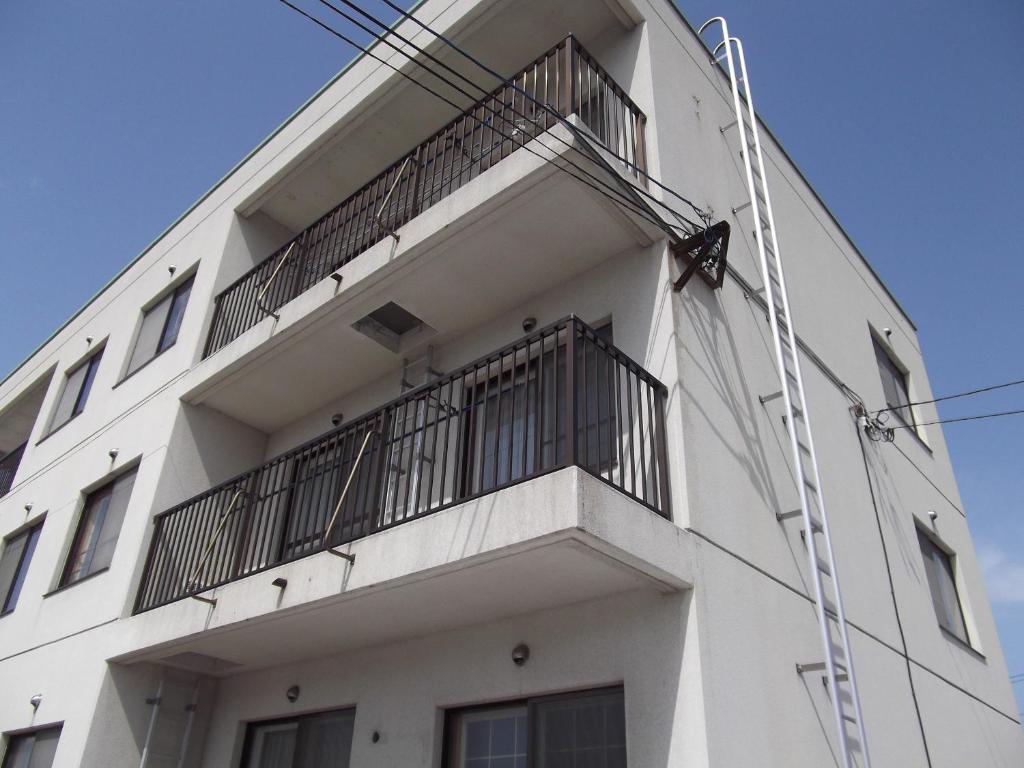 un edificio blanco con una escalera a un lado en Frontier Sunrise, en Kami-furano