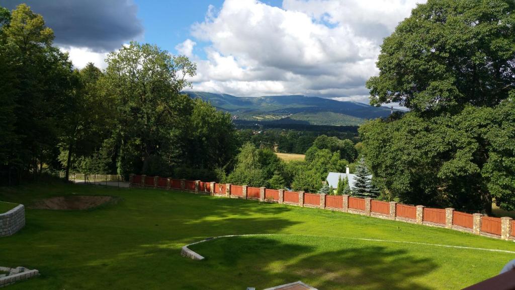 een groene tuin met een hek en bergen op de achtergrond bij Sarna Karkonosze in Bukowiec