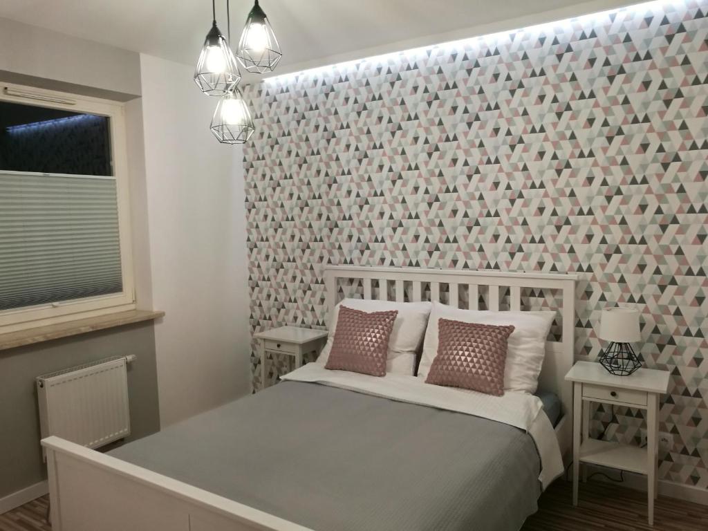 ルブリンにあるApartament Miniの白いベッドと壁紙で覆われたベッドルーム1室が備わります。