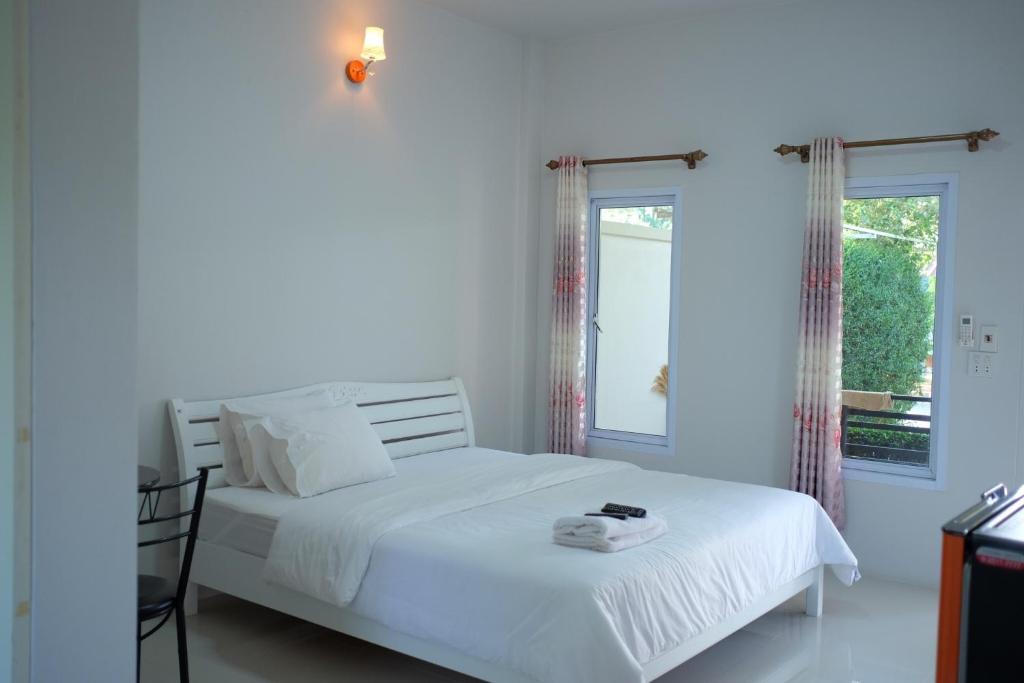 a white bedroom with a white bed and a window at Khong Chom Jan in Nong Khai