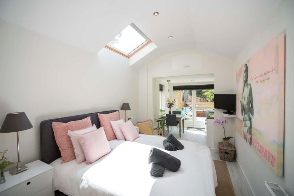 1 dormitorio con 2 camas blancas con almohadas rosas en The Bond Studio FREE PARKING en Zandvoort