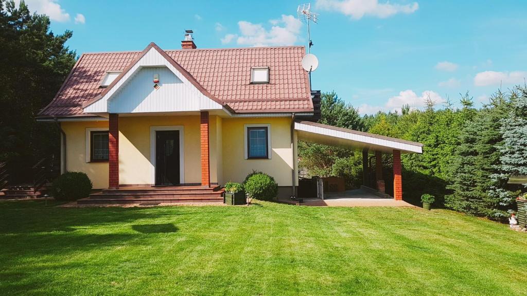 una pequeña casa amarilla con un patio de césped en Przystanek Kaszuby z balią i jacuzzi, en Wąglikowice