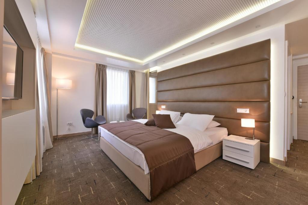 a bedroom with a large bed with a brown headboard at Hotel City One Diamond in Sarajevo