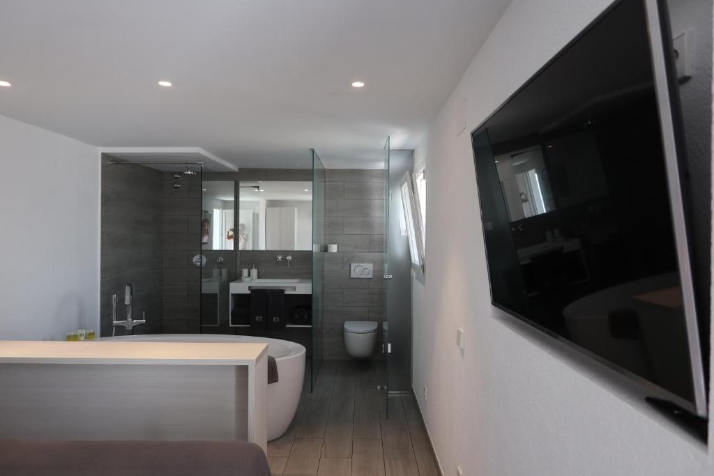 La salle de bains est pourvue d'une baignoire et d'une télévision murale. dans l'établissement Carpe Diem Cadaqués, à Cadaqués