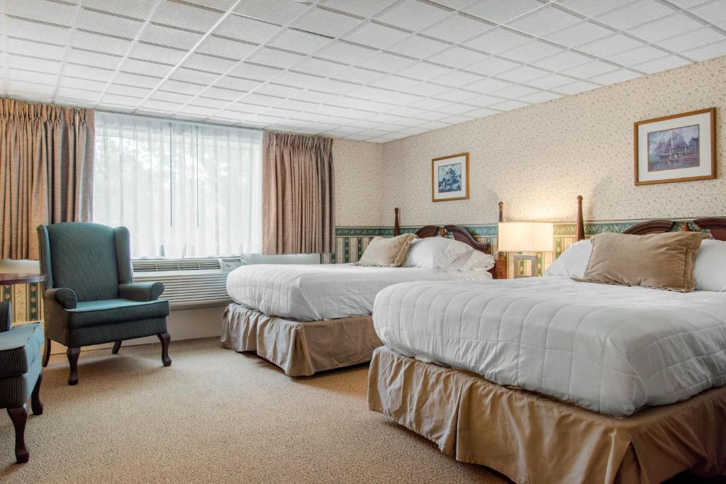 a hotel room with two beds and a chair at Coachman Inn in Kittery