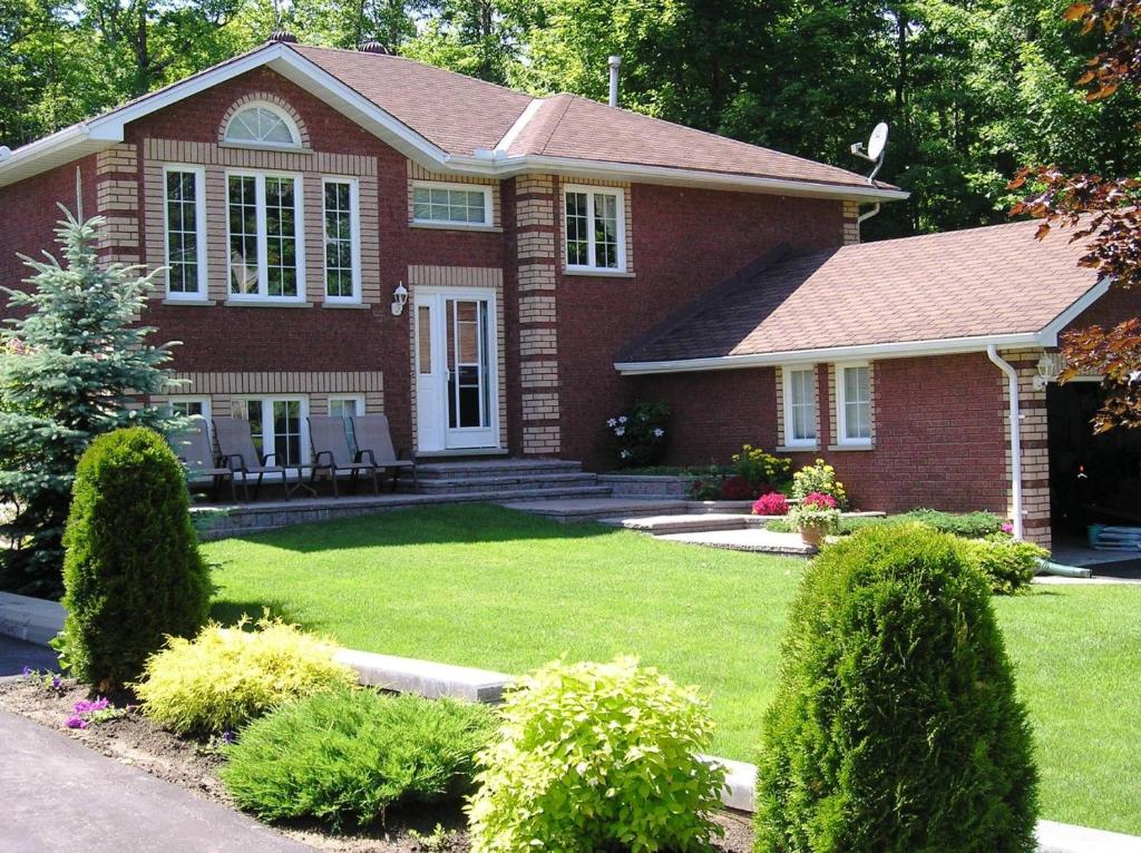 a red brick house with a green yard at Tucked Inn the Harbour B&B in Victoria Harbour