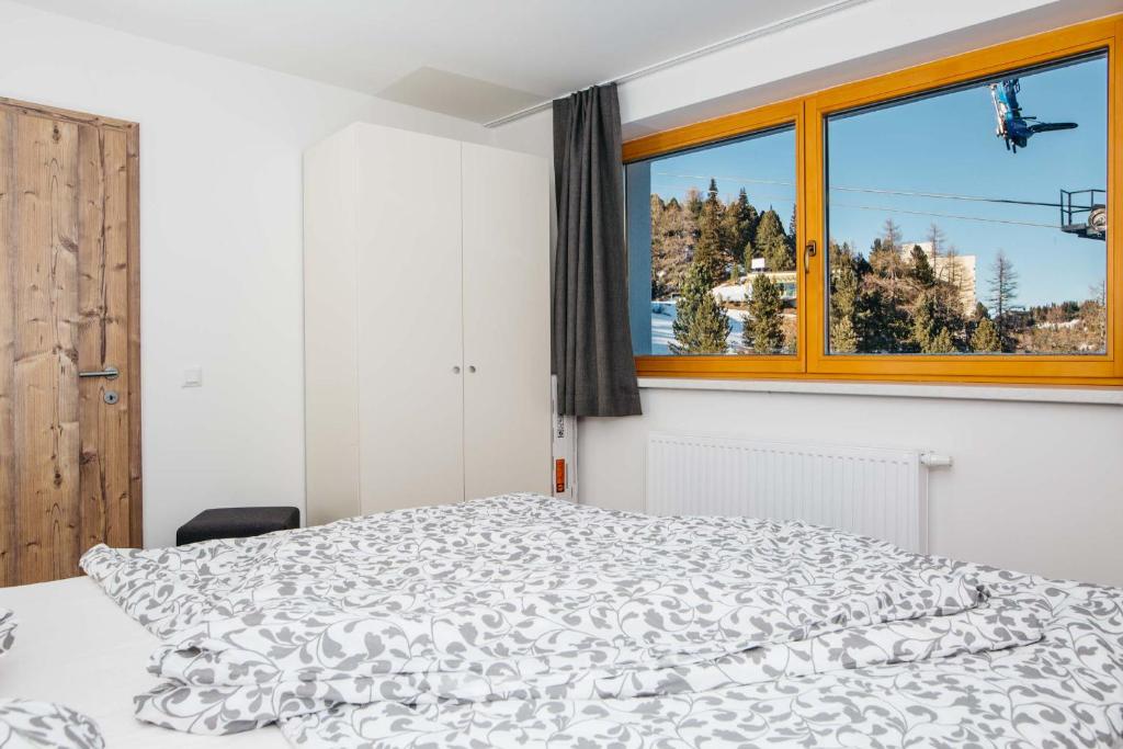 a white bedroom with a bed and a window at FeWo Nocky- Wandern- Berge- Auszeit- Liftnähe in Turracher Hohe