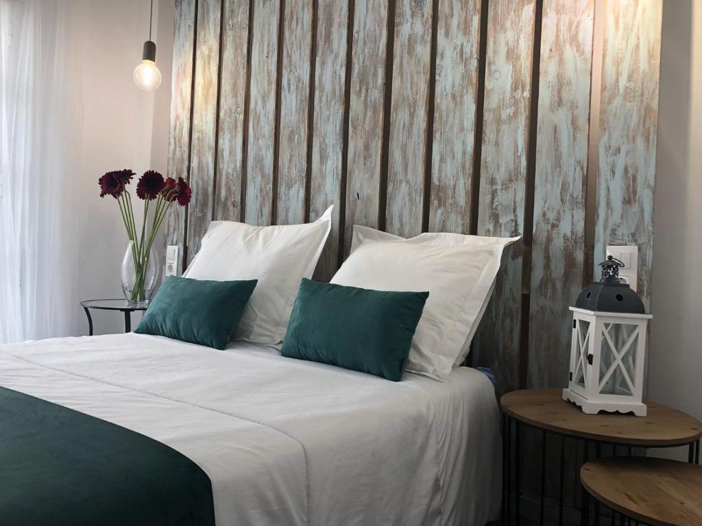 コニル・デ・ラ・フロンテーラにあるConil apartamentos la Dama y el Vagabundoのベッドルーム1室(白いシーツと緑の枕が備わるベッド1台付)