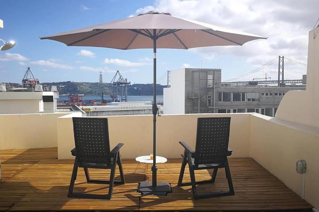 dos sillas y una mesa con una sombrilla en el techo en Apartamento sobre o Rio, en Lisboa