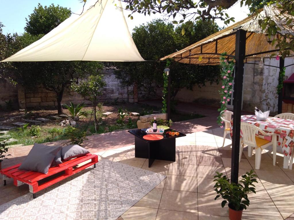 un patio con una mesa y una sombrilla blanca en Corte dei Giorgi, en Vernole