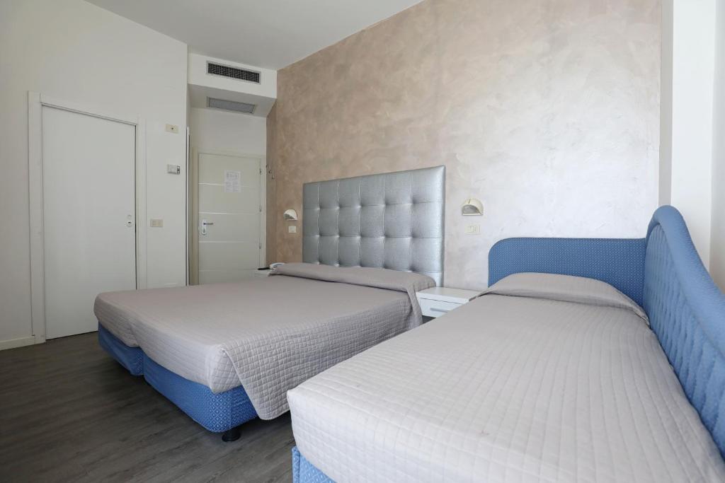 2 letti in una camera da letto con blu e bianco di Hotel Daniel's FRONTE MARE a Riccione