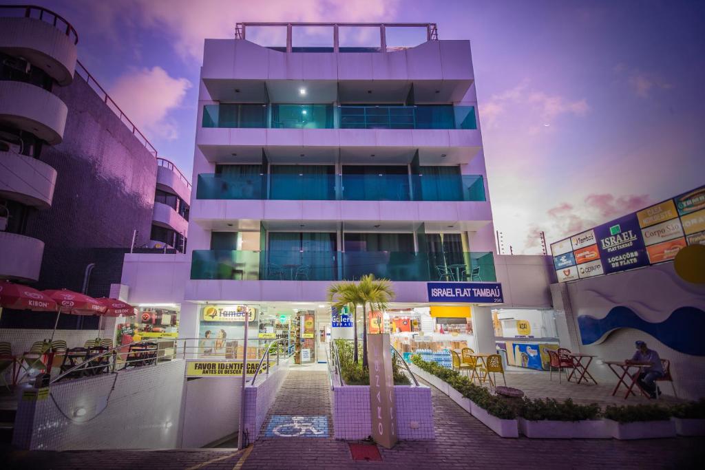 een hoog gebouw met tafels en stoelen ervoor bij ISRAEL TAMBAU Flat by PenareiaTurBr in João Pessoa