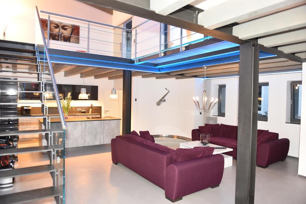 uma sala de estar com sofás roxos e uma escadaria em The Fountain Loft - 170sqm em Dortmund