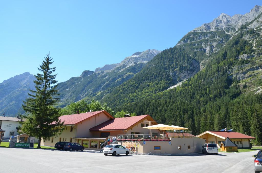 ein Gebäude mit einem Auto, das vor einem Berg parkt in der Unterkunft Gasthaus-Pension Reiterklause in Leutasch