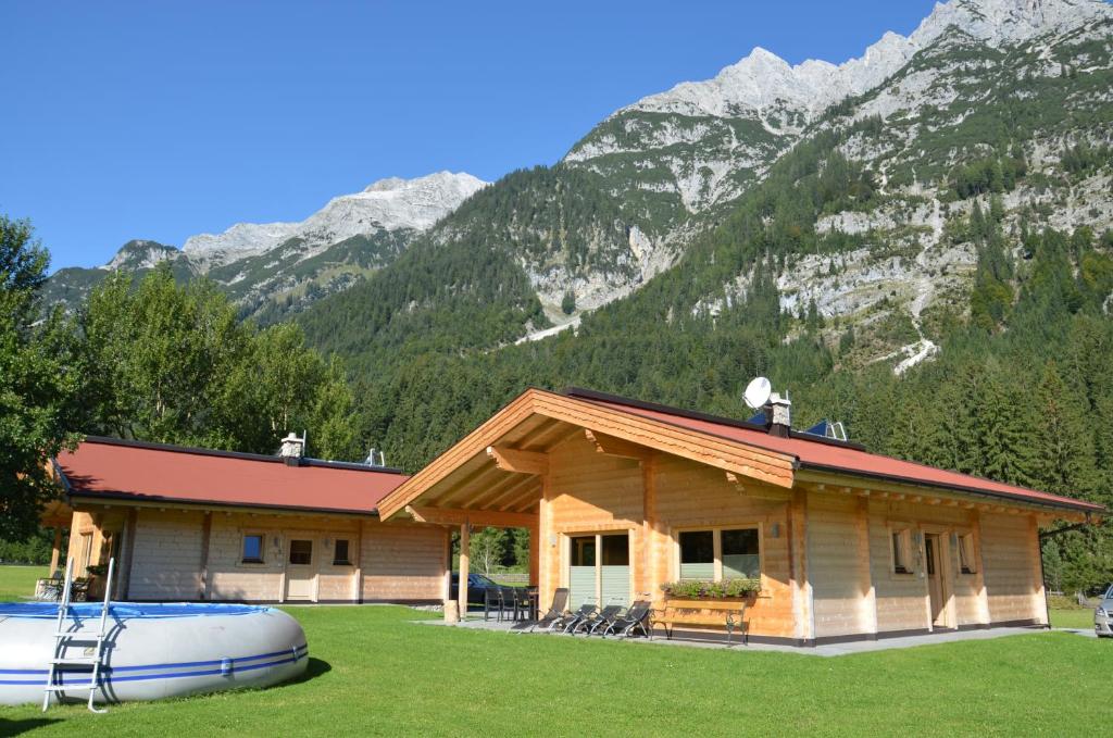 domek z bali z łodzią przed górą w obiekcie Gasthaus-Pension Reiterklause w mieście Leutasch