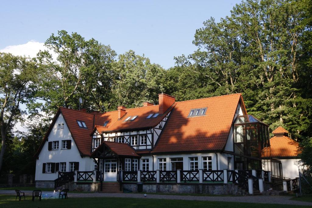 een groot wit huis met een oranje dak bij Leśniczówka Nibork in Nidzica