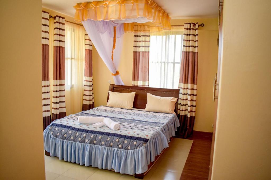 a bedroom with a bed with a canopy and windows at Lakeview LUX Apartment in Kisumu
