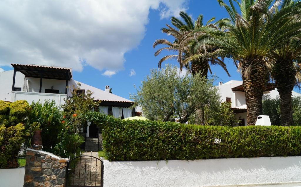una casa blanca con palmeras y una valla en Halkidiki Trikorfo Luxury Maisonette, en Gerakini