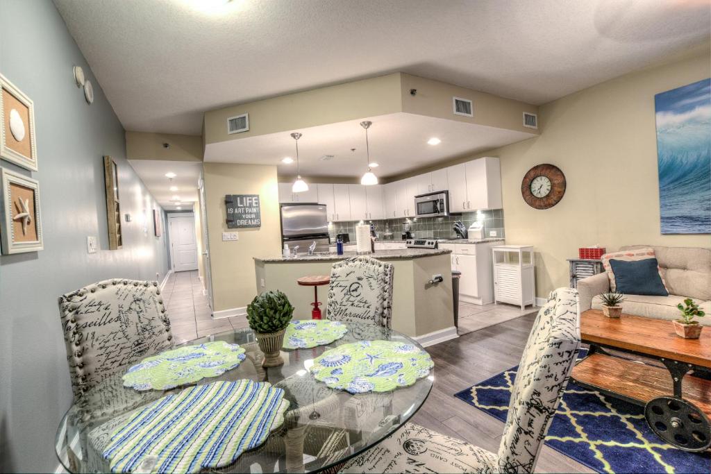 a dining room and kitchen with a glass table and chairs at Grand Panama Resort 2-202 By Aneliya in Panama City Beach