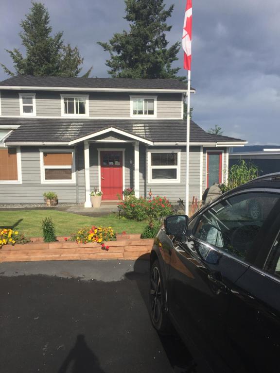 een auto geparkeerd voor een huis met een Canadese vlag bij Money Pennies Bed and Breakfast in Campbell River