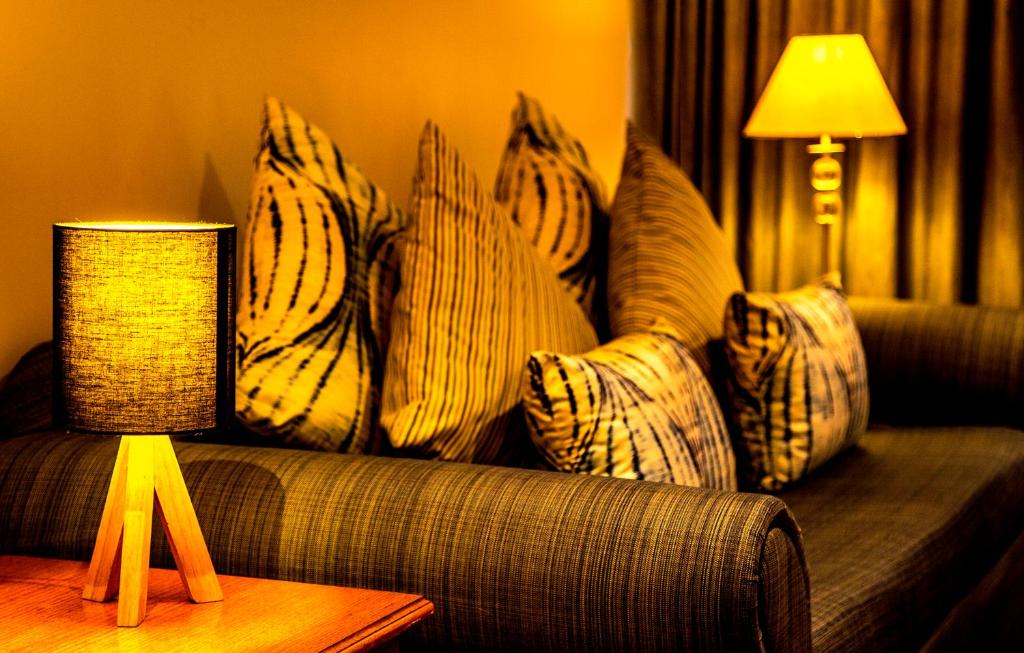 a living room with a couch with pillows and a lamp at The Pearl South Pacific Resort, Spa & Golf Course in Pacific Harbour