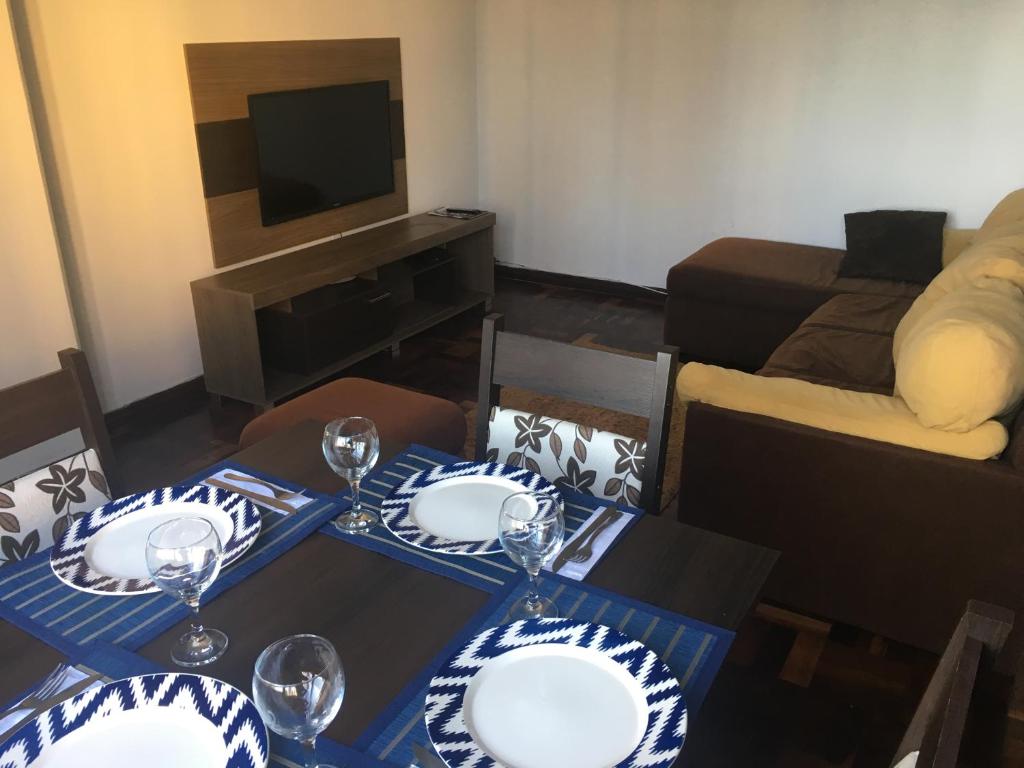 una sala de estar con una mesa con platos y copas de vino en AP na Rua das Flores, en Curitiba