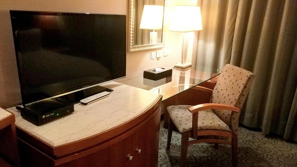 a hotel room with a desk with a large flat screen tv at Elegance Hotel in Taipei