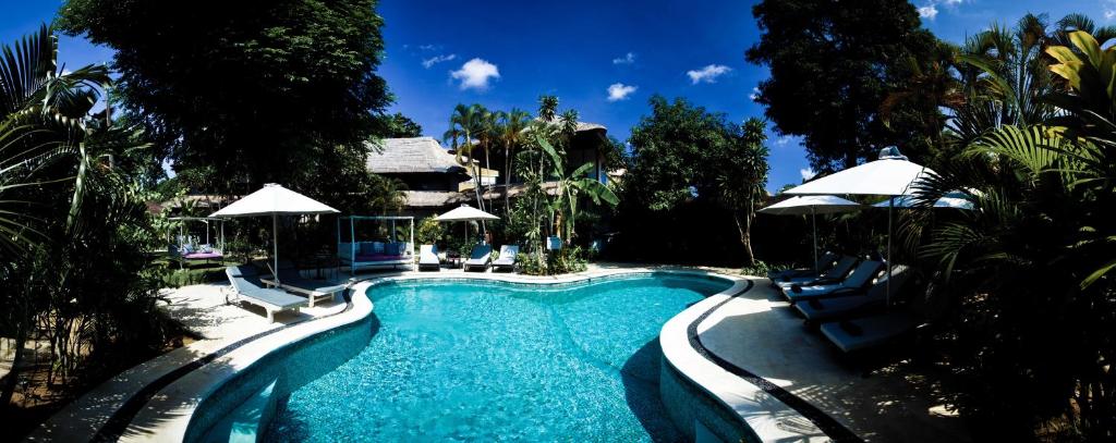 a swimming pool with chairs and umbrellas at Pearl Boutique Hotel Adult only in Legian