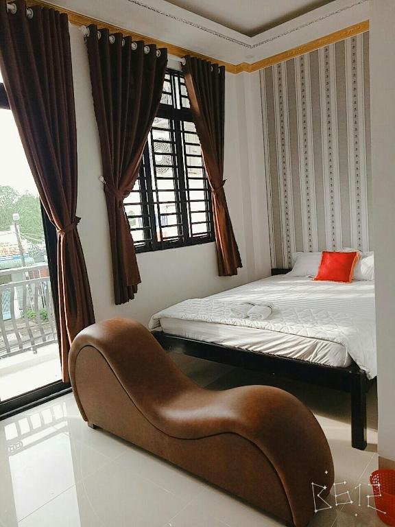 a bedroom with a bed and a bench in front of a window at Hanh Phat 2 Guesthouse in Cái Răng