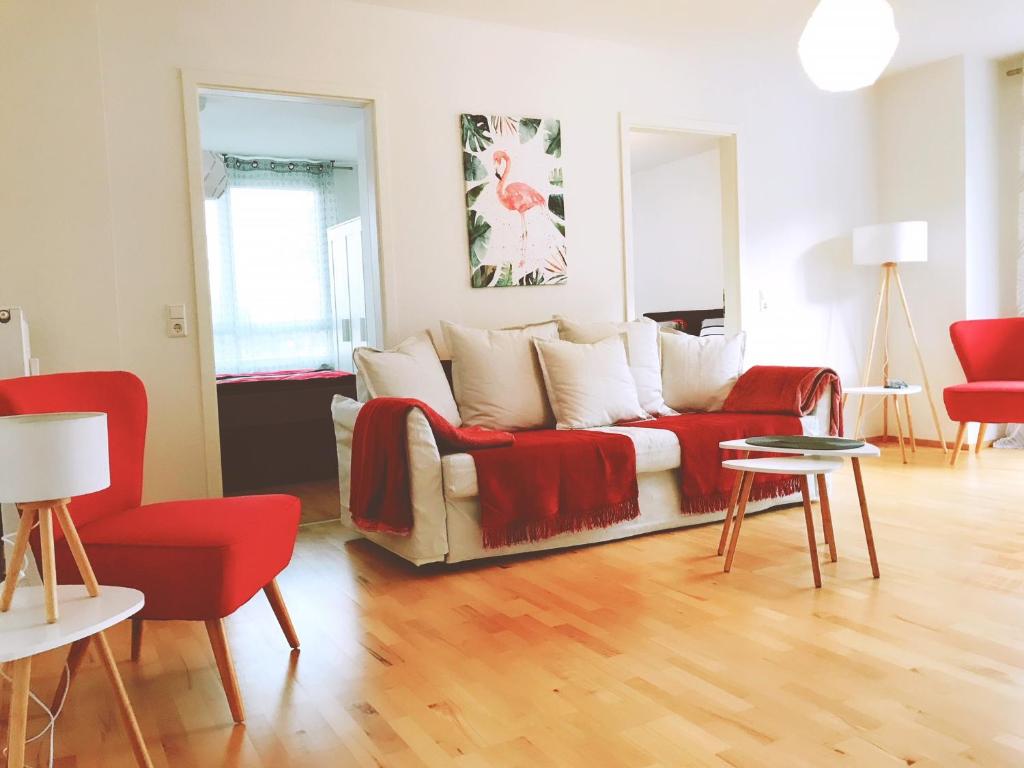 アレンスバッハにあるBodenSEE Apartment Allensbach FEWO 1のリビングルーム(ソファ、赤い椅子付)